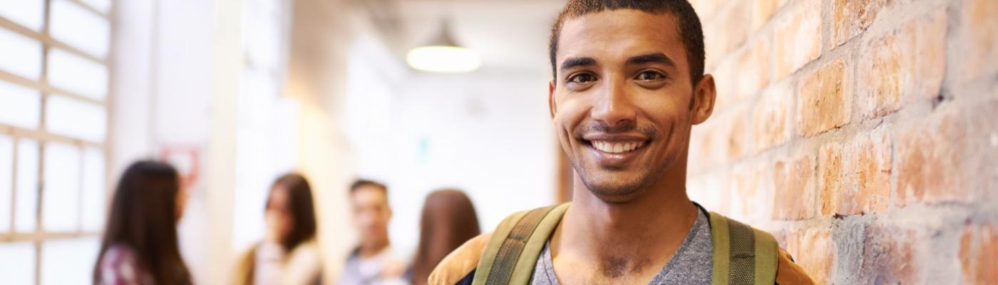 Jeune étudiant souriant dans un couloir